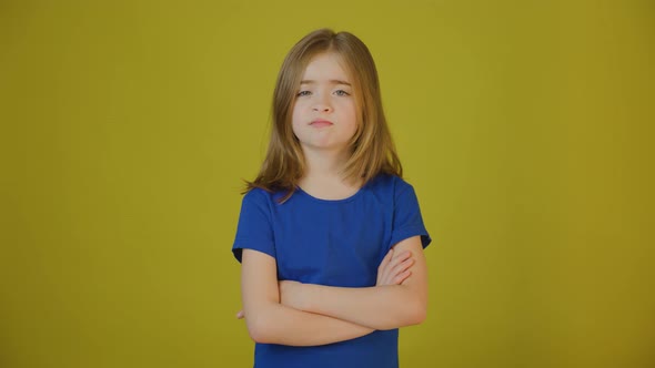 Upset Child with Hands Crossed on Yellow Background in Studio
