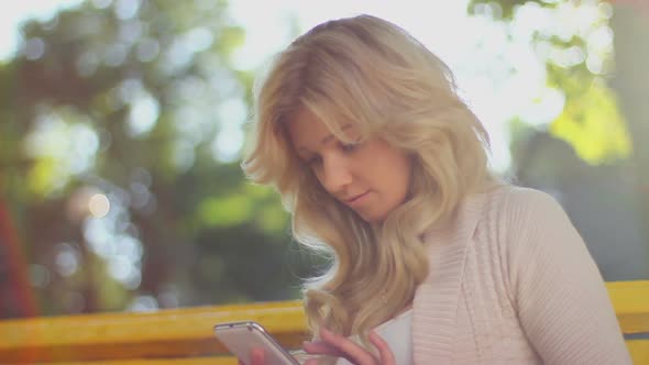 Woman Scrolling Pictures on Phone Smiling Enjoying Bench Park