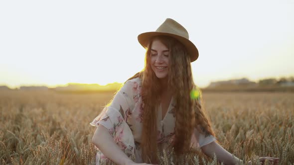 Happy Young Lady Smiling and Playing with Wheat Ears Among Field on Sunset