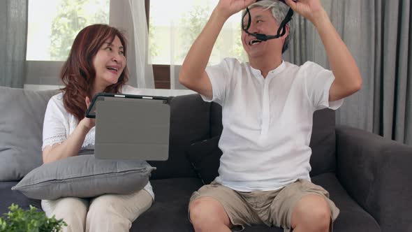 Asian elderly couple using tablet and virtual reality simulator playing games.