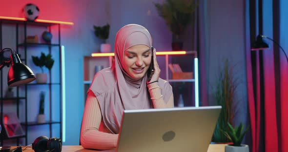 Arabic Woman Getting Good News on Laptop when Sitting at Her Workplace at Home