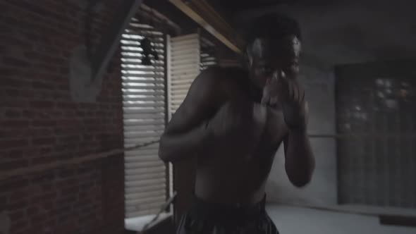 Muscular Afro-American Fighter Shadow Boxing in Dingy Gym