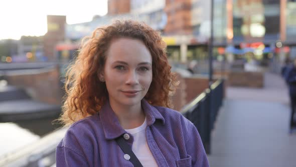 Redheaded woman standing in the city, looking at camera