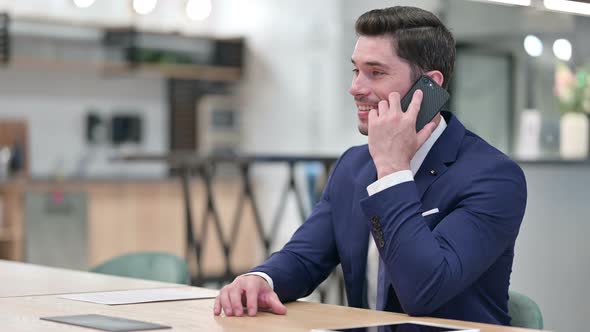 Cheerful Businessman Talking on Smartphone in Office 