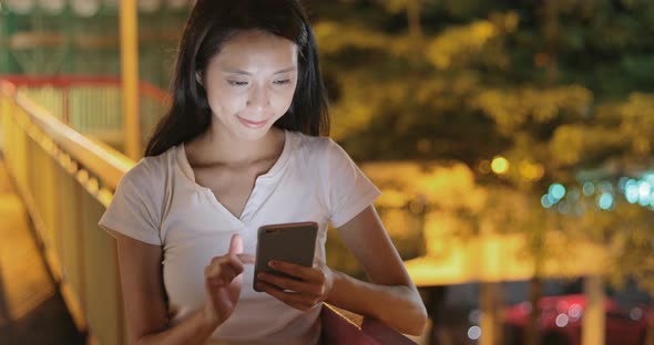 Young woman looking at mobile phone in city at night