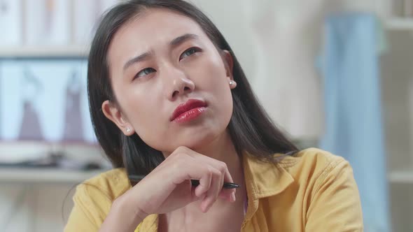 Close Up Of Asian Female Designer Thinking While Designing Clothes In The Studio