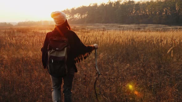 Female Hiker Walks Along Meadow Among Dry Grass