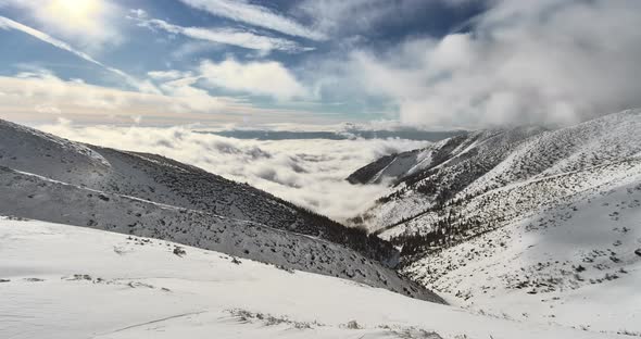 Clouds rolling over the snow covered valley between high alpine peaks in Tatras, Slovakia