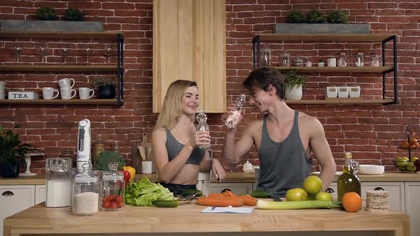 Cute sport couple drinking water in the kitchen.