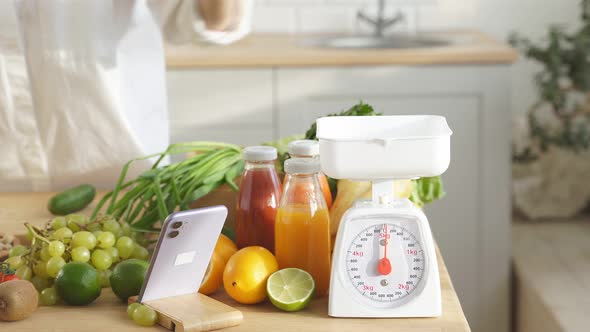 A Woman at Home in the Kitchen Weighs Vegetables on a Scale Closeup Without a Face