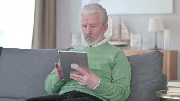 Pensive Old Man Using Tablet at Home
