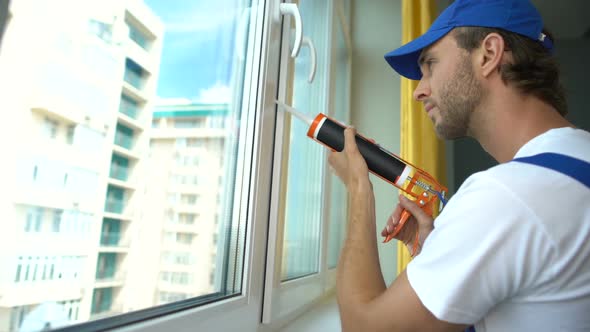 Man Uses Silicone Adhesive With Glue Gun to Repair Worn Window, Sound Insulation