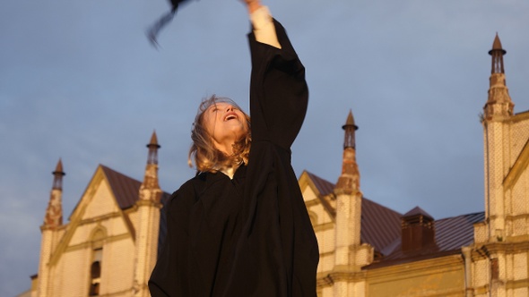 Graduation - girl throws her hat in the air and smiles