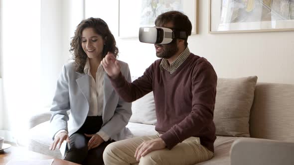 Bearded Young Man Gesturing While Using VR Headset at Home