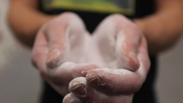 Close-up of a young man putting chalk on his hands in an indoor climbing gym.