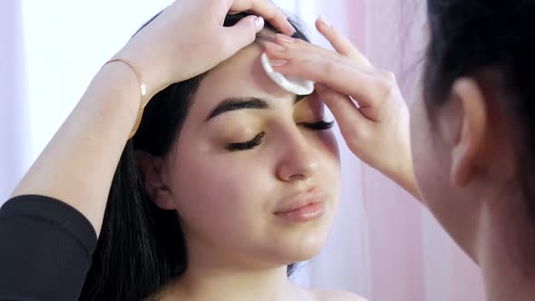 The Makeup Artist Cleans the Face with a Special Solution and a Cotton Pad Before Applying Makeup