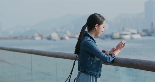 Woman use of mobile phone and standing at the seaside bay