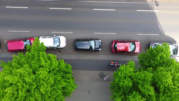 Pedestrians on sidewalk, cars parked in street, rails of an elevated train Aerial view flight bird's