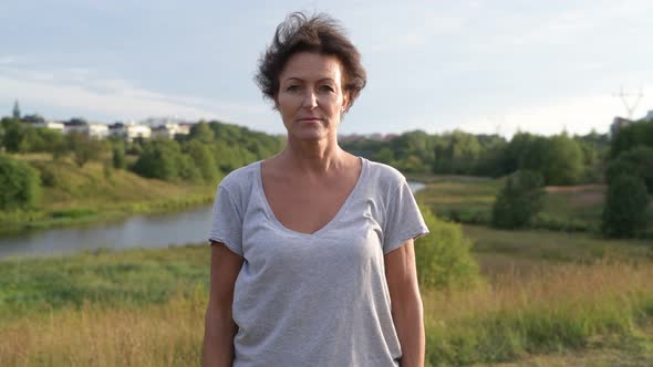 Happy Mature Beautiful Woman Smiling Against Relaxing View of Nature