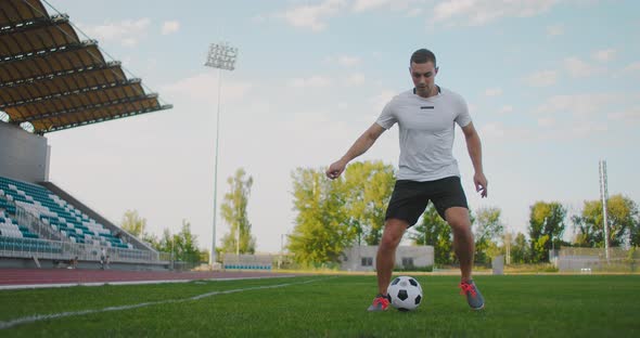 A Soccer Player at the Stadium Demonstrates Dribbling with a Soccer Ball While Leading a Sword While