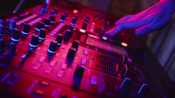 Professional Confident DJ is Adjusting Fader on Digital Music Console in Neon Light in Nightclub