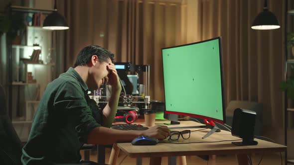 Frustrated Asian Man Work On 3D Printer And Personal Computer With Mock Up Green Screen Display