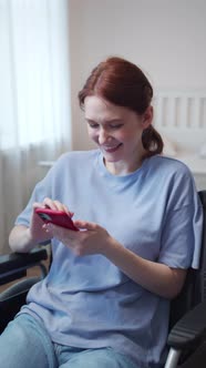 A Disabled Woman is Sitting in Her Wheelchair and Looking Through the Internet