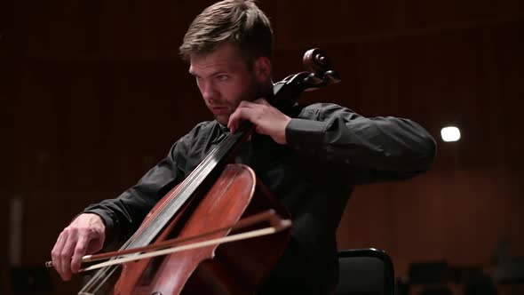Young man in black clothes playing the cello