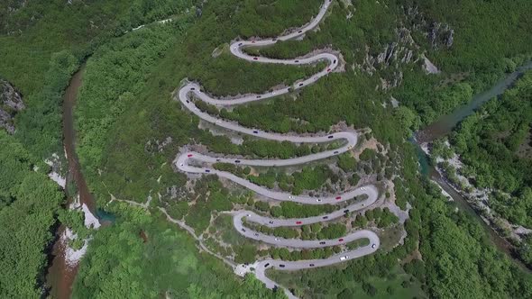 Drone shot of lots of race cars on curvy road in the mountain near Papingo, Greece.
