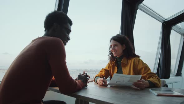 Diverse Colleagues Discussing Business Report in Rooftop Office