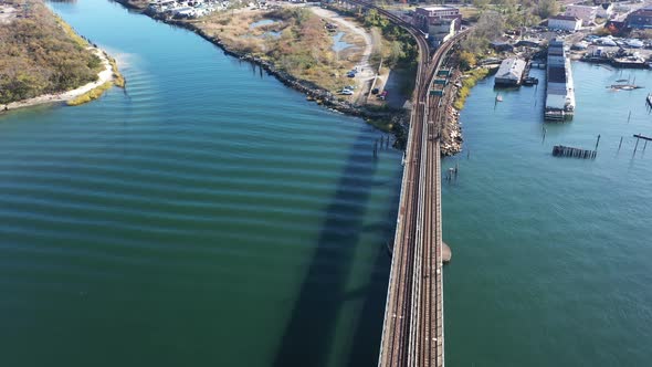 A high angle shot over elevated train tracks crossing a bay in Queens, NY. The camera dolly in direc