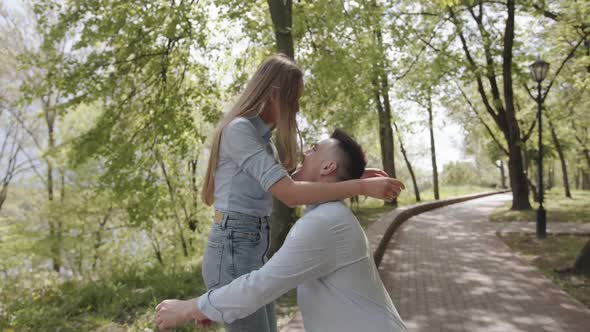 A Young Man Picks Up His Beloved in His Arms and Circles on the Path of the Park