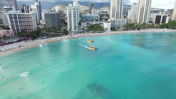 Beautiful rotating 4k aerial drone shot of Waikiki Beach as sunset dinner cruise boats land on the b