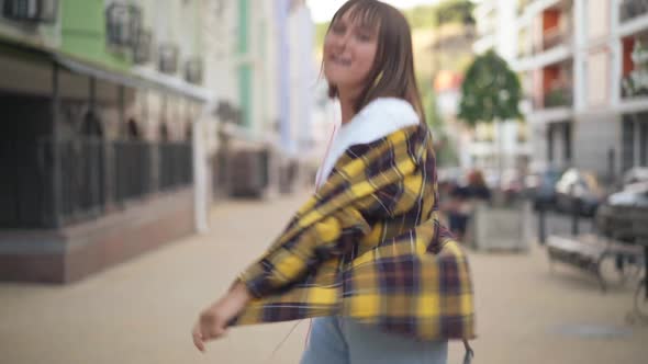 Portrait of Joyful Excited Teenage Girl Dancing on City Street Walking Listening to Music in