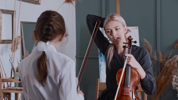 Young Woman Teacher Having a Violin Lesson with a Little Girl