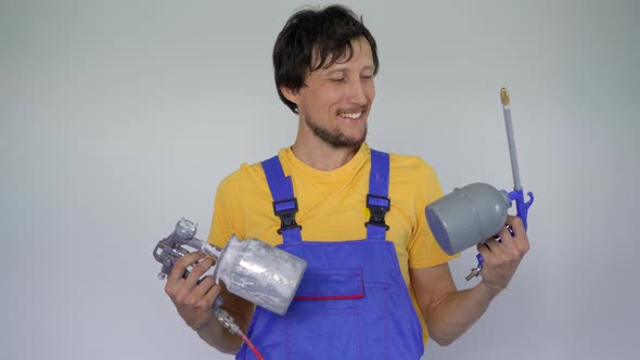 A Man Professional Home Renovator Holds Spray Painting Devices in His Arms