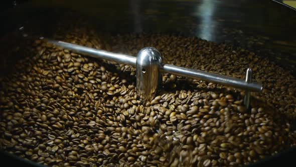 Coffee beans being stirred on cooling plate after being roasted medium shot