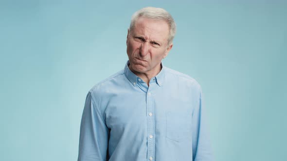 Angry Grumpy Senior Man Scolding to Camera with Fist Feeling Furious and Rageful Blue Studio