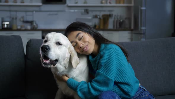 Young Hindu Woman Petting and Hugging Dog on Sofa