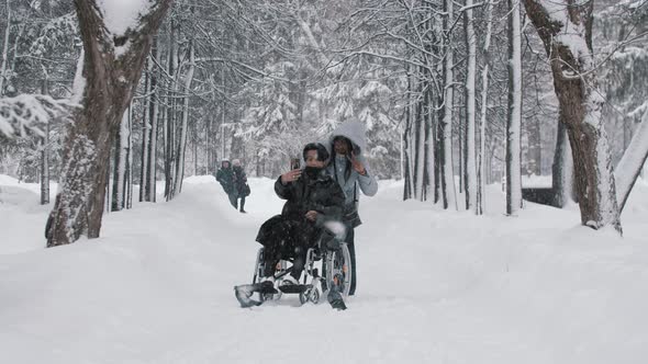 Young Couple of Asian Guy in the Wheelchair and His Black Girlfriend Taking a Selfie in Winter