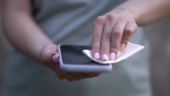 Woman Wiping Mobile Phone with a Napkin
