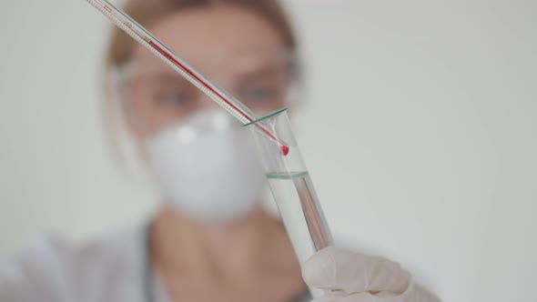 A Young Lab Worker Makes a Blood Test of a Person with a Coronavirus Covid-19. A Test Tube with a