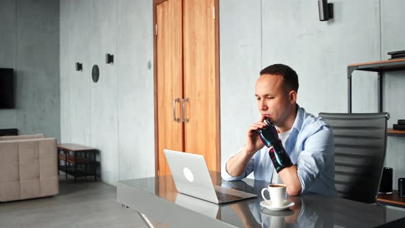 Thoughtful cyborg programmer with black bio hand prothesis looks at laptop screen