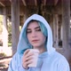 Blue haired teenage girl in oversize hoodie drinking coffee to go against bridge pillars - VideoHive Item for Sale