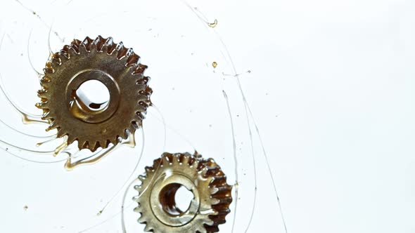 Super Slow Motion Shot of Rotating and Splashing Metal Cogwheels on White Background at 1000 Fps