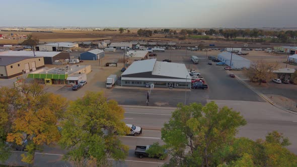 A small industrial park in an agricultural community.  A truck pulls into the parking lot.  Pressing