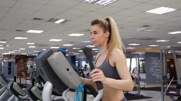 Young woman working out on orbi track at gym exercising