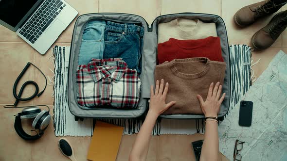 Woman Packs Suitcase for Travel or Adventure