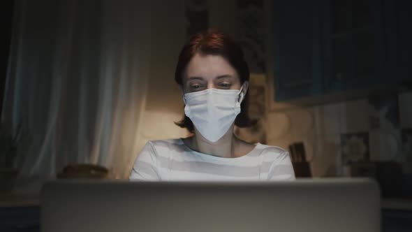 Young Girl In The Kitchen With Laptop. Young Woman Working Remotely At Home Because Of Pandemic