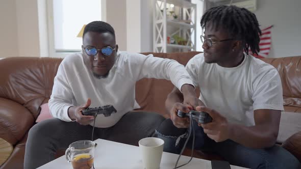 Joyful African American Man Cheating in Video Game Closing Eyes of Friend